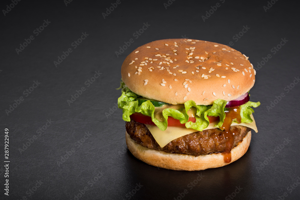 Hamburger with  meat, tomatoes, salad, onions on a black. Copy space