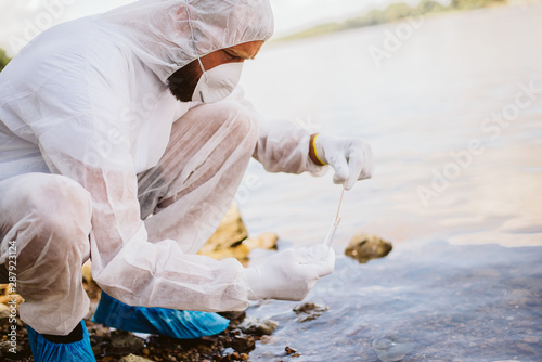 Canvas Print A man in a protective suit takes a water sample