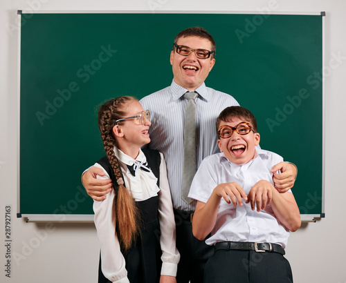 Portrait of a teacher, schoolboy and schoolgirl with old fashioned eyeglasses posing on blackboard background - back to school and education concept photo