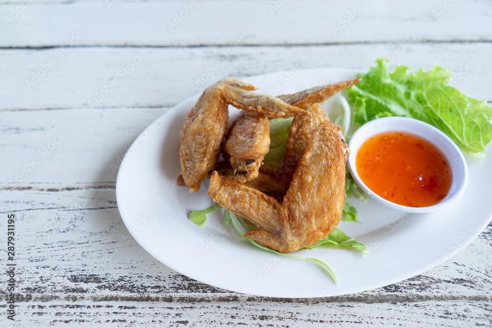 Fried chicken wings with chilli sauce in white plate on wooden background. Fried chicken wings with chilli sauce in white plate on wooden background.