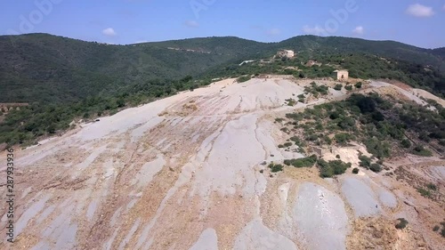 Drone shot turning on a partly cultivated hills landscape in Sardinia Italy. some abandoned villas are visible at the top of the hills photo