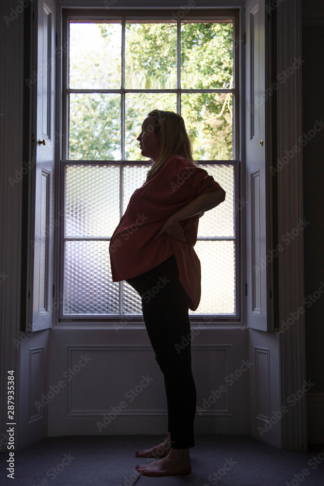 Silhouette of a prgnant woman standing infront of a window Silhouette of a prgnant woman standing infront of a window