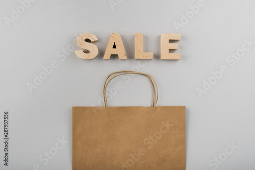 Top view of sale letters with paper bag on plain background