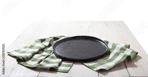 Black plate or tray  or pizza board  with tablecloth on wooden table. Top view mockup