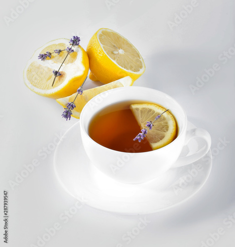 Cup of hot tea with lemon and lavender on white background