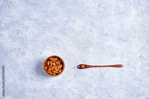 Almonds in brown bowl on wooden background top view