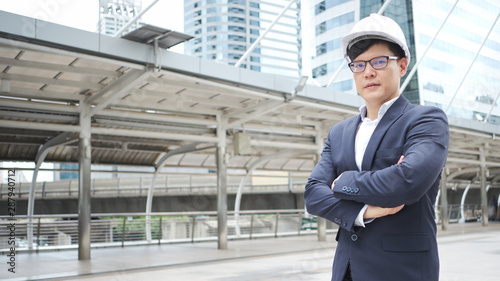 Wallpaper Mural Confident Asian Businessman or Engineer is standing, his hand arms crossed and looking ahead with a vision that strives for success in a Business district full of tall buildings. Torontodigital.ca