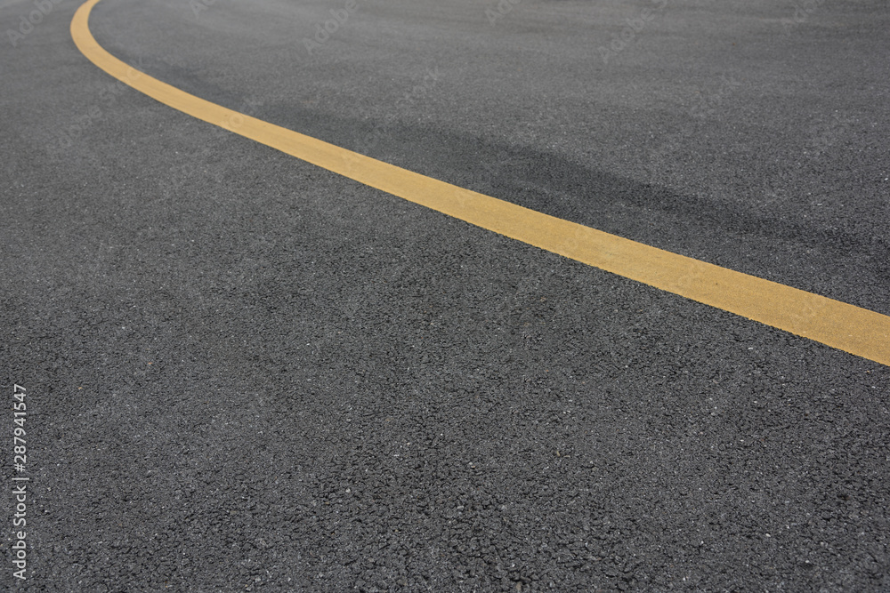 Low angle view of asphalt bend yellow paint line