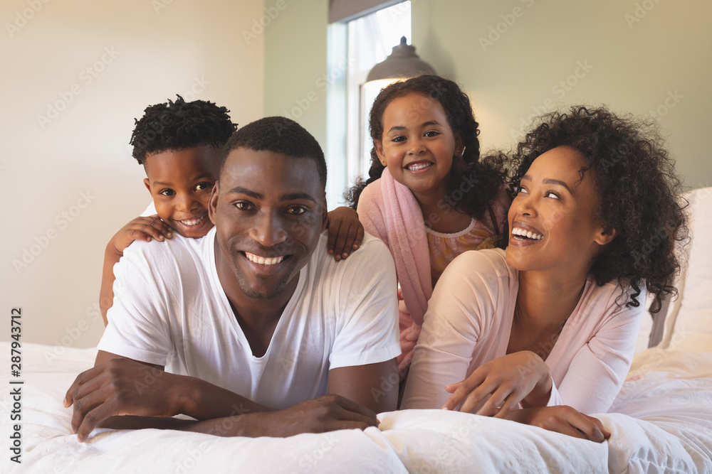 Happy African American family lying on bed and looking at camera Happy African American family lying on bed and looking at camera