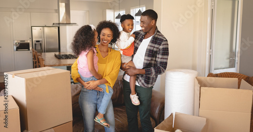 Happy African American parents with their children and boxes moving in new house