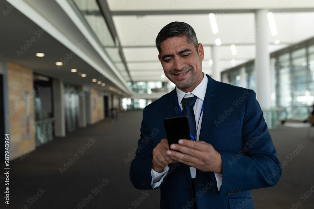 Front view of businessman laughing in using his mobile phone in office lobby Front view of businessman laughing in using his mobile phone in office lobby
