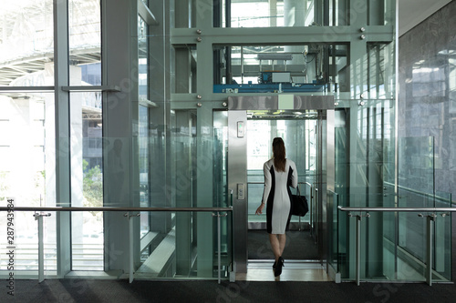 Caucasian female executive getting in modern elevator at office