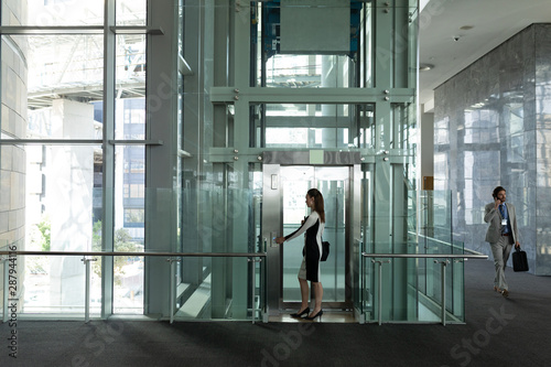 Caucasian female executive getting in modern elevator at office photo