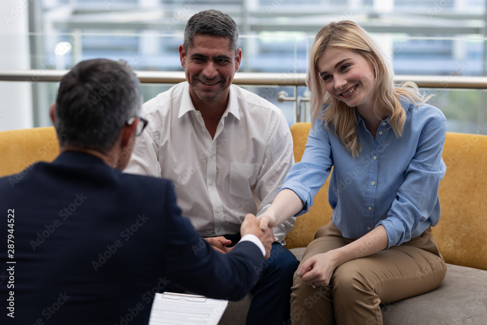 Caucasians business executives shaking hand while sitting on the sofa Caucasians business executives shaking hand while sitting on the sofa