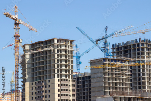 Construction site background. Hoisting cranes and new multi-storey buildings. tower crane and unfinished high-rise building. many cranes © Elena