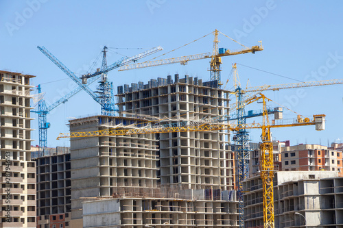 Construction site background. Hoisting cranes and new multi-storey buildings. tower crane and unfinished high-rise building. many cranes