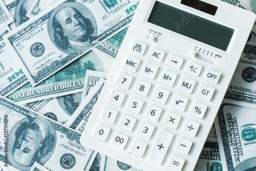 top view of white calculator on dollar banknotes