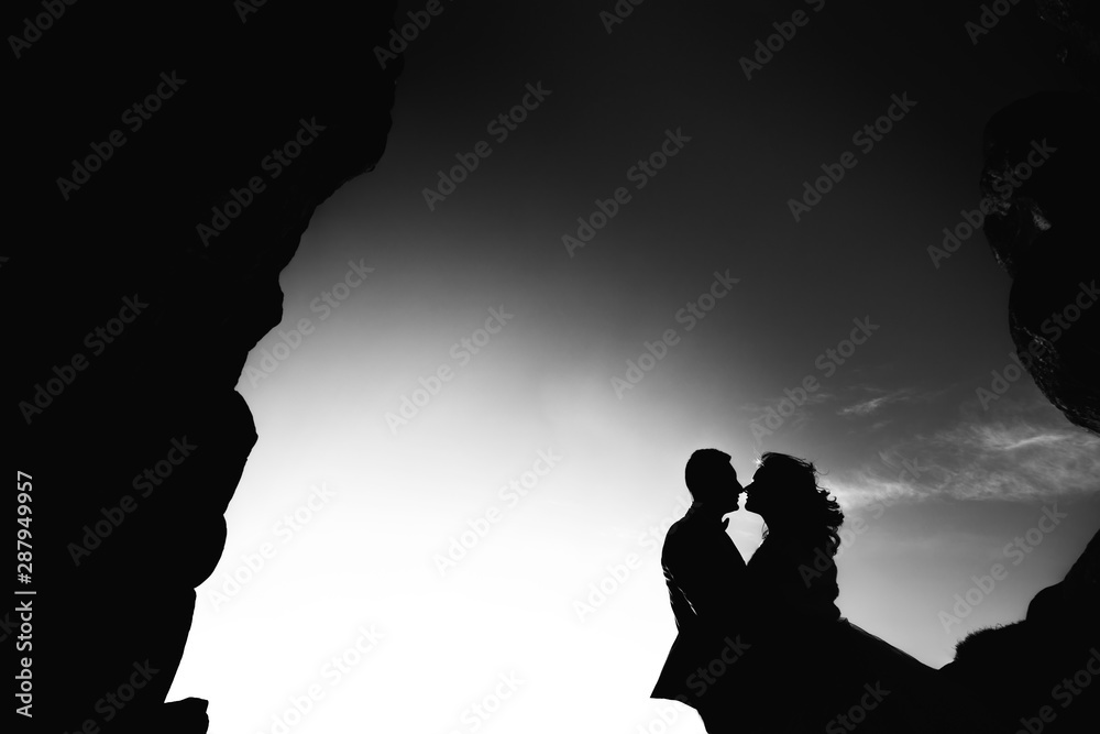 silhouette of newlyweds hugging each other on a background of cl