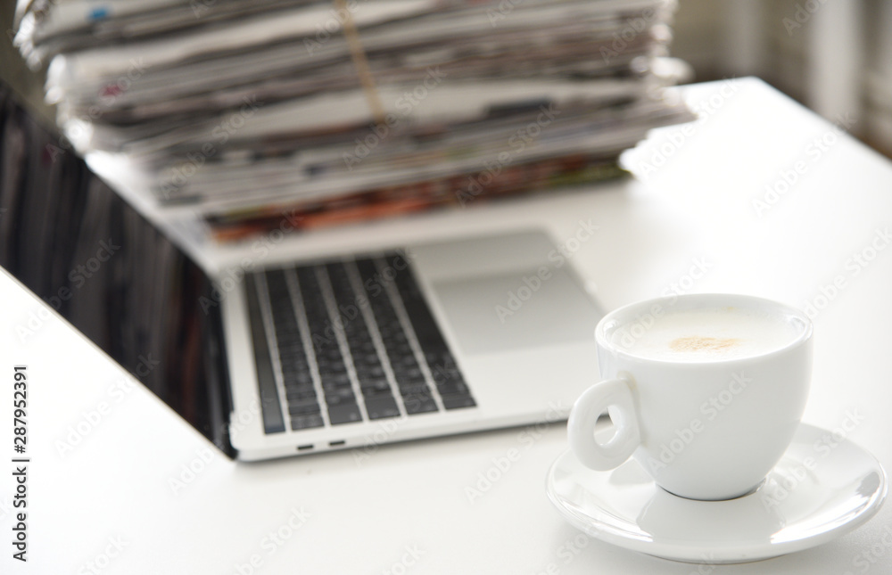 Take a break concept picture, pile of newspapers, opened laptop and cup of coffee on the table Take a break concept picture, pile of newspapers, opened laptop and cup of coffee on the table