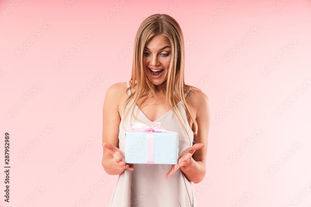 Image of joyous young woman wearing dress expressing surprise and holding gift box Image of joyous young woman wearing dress expressing surprise and holding gift box