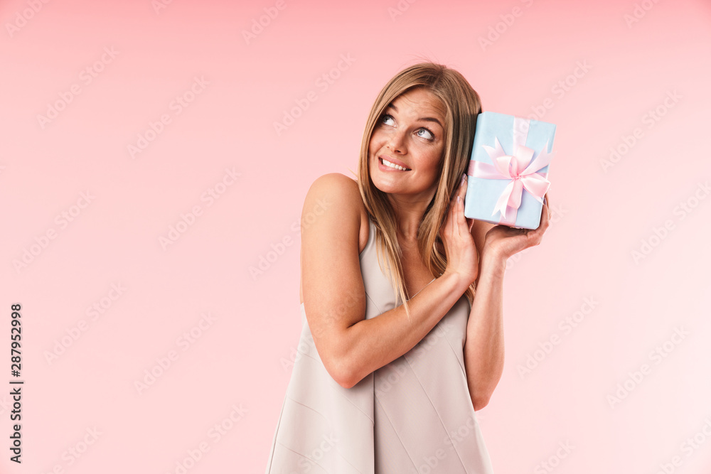 Image of lovely young woman wearing dress expressing surprise and holding gift box Image of lovely young woman wearing dress expressing surprise and holding gift box