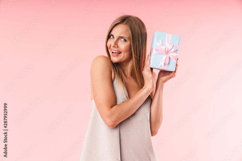 Image of pretty young woman wearing dress smiling and holding gift box Image of pretty young woman wearing dress smiling and holding gift box