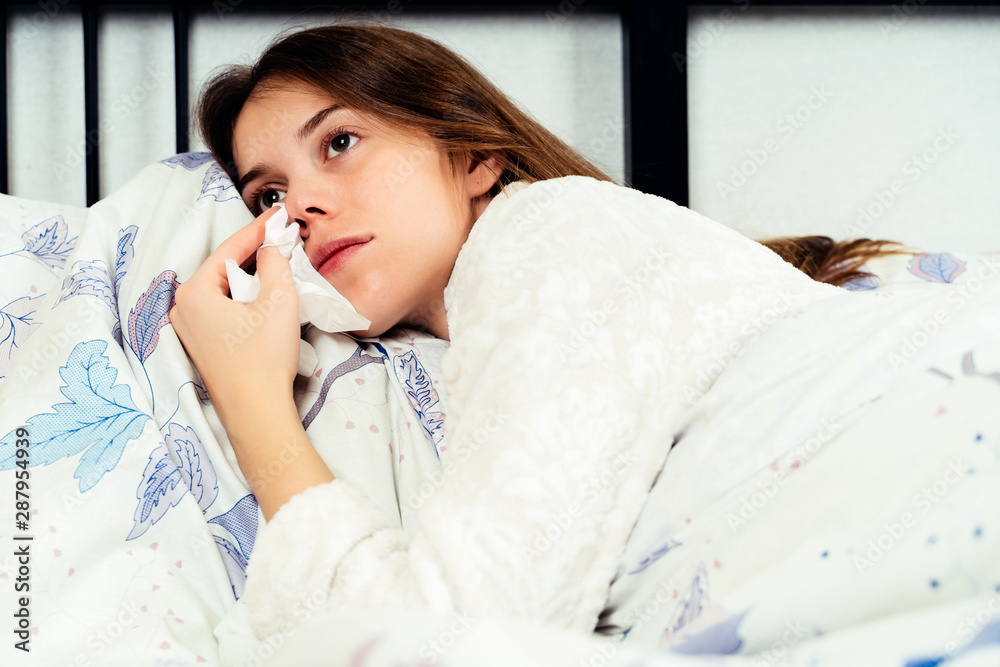 Young woman lying alone on the bed and crying