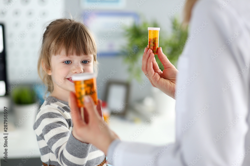 Portrait of cheerful baby visiting family doctor. Pediatrician giving medicaments to smiling little girl. Health care and prevention concept. Blurred background Portrait of cheerful baby visiting family doctor. Pediatrician giving medicaments to smiling little girl. Health care and prevention concept. Blurred background