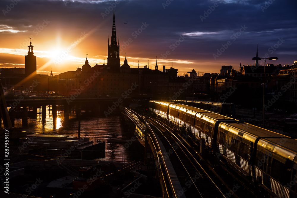 Stockholm city skyline. The view of Old Town, Gamla Stan, and Riddarholmen Church from The Central Bridge Centralbron with local trains on it during sunset. Sweden.