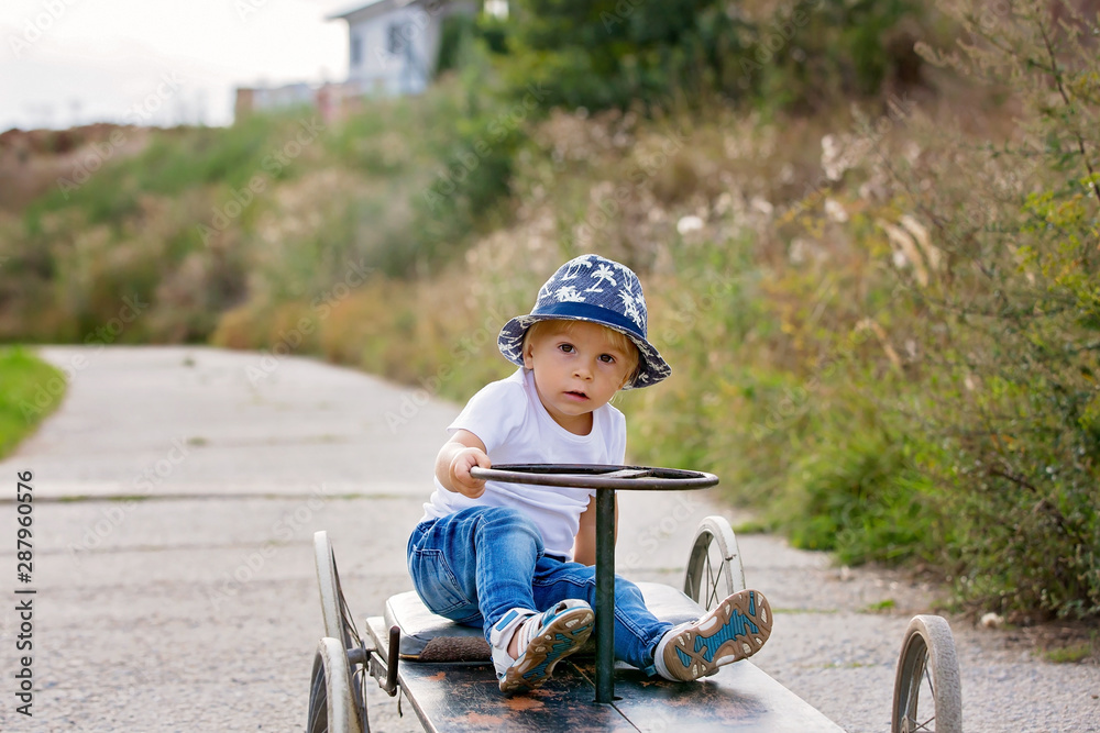 Adorable toddler boy, riding old retro car with four wheels