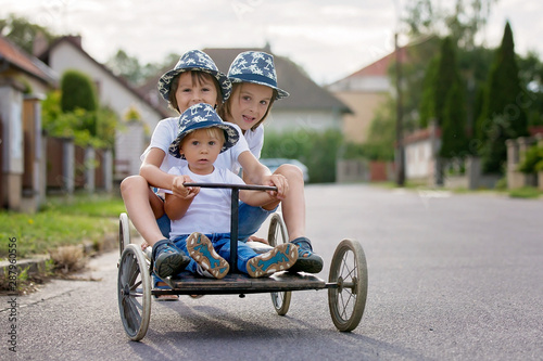 Happy children, boys, riding old retro car with four wheels © Tomsickova