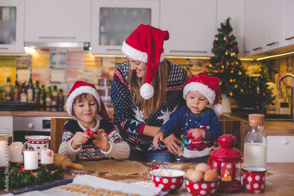 Sweet toddler child and his older brother, boys, helping mommy preparing Christmas cookies at home Sweet toddler child and his older brother, boys, helping mommy preparing Christmas cookies at home
