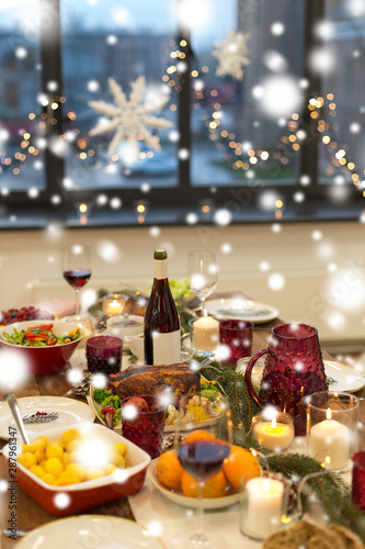 christmas dinner and eating concept - food and drinks on table at home over snow