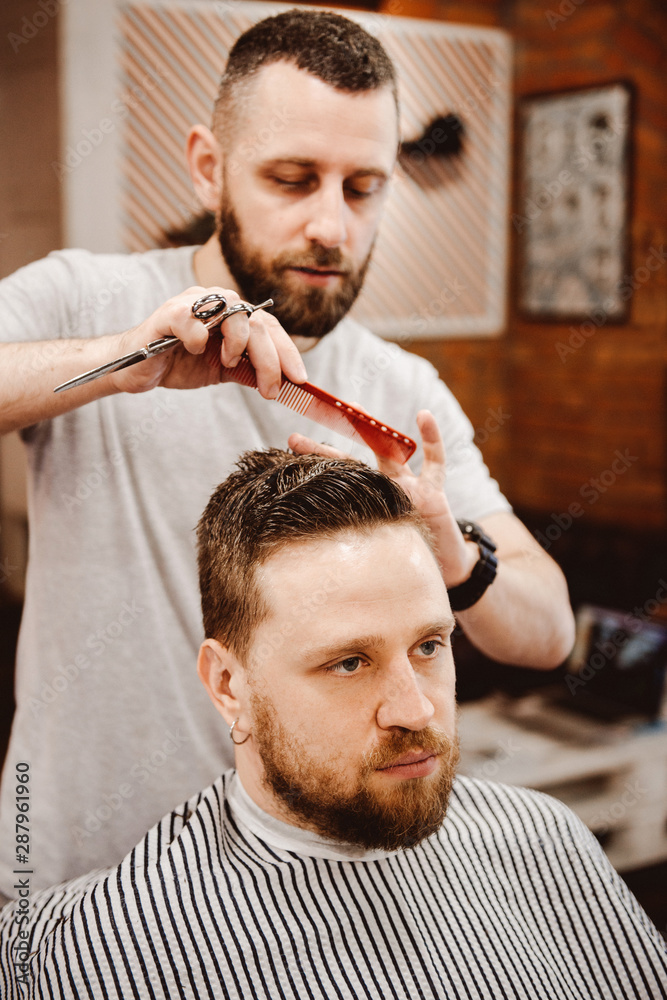 Fototapeta premium Hipster client getting a haircut at barber shop
