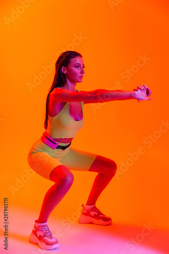 Full length photo of pretty brunette woman wearing formfitting sportswear doing workout