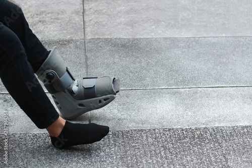 A Asian girl is wearing a ankle support boot after surgery. photo