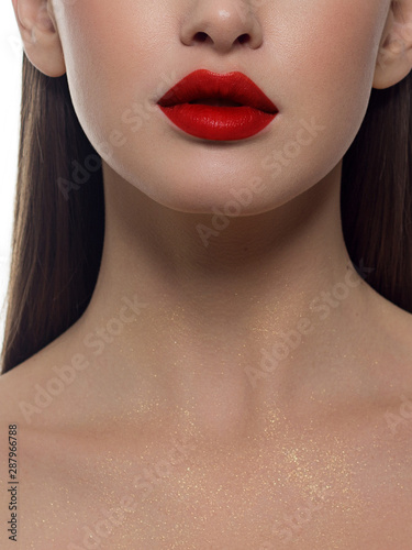 Cosmetics, makeup and trends. Bright lip gloss and lipstick on lips. Closeup of beautiful female mouth with red lip makeup. Beautiful part of female face. Perfect clean skin in red light