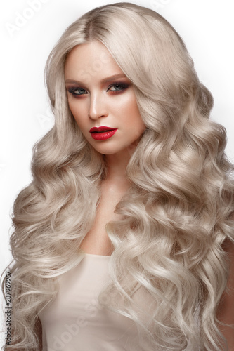 Beautiful blonde in a Hollywood manner with curls, natural makeup and red lips. Beauty face and hair.