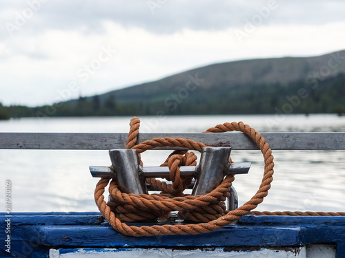 A coil of orange rope around cleats on the stern of a blue wooden boat.