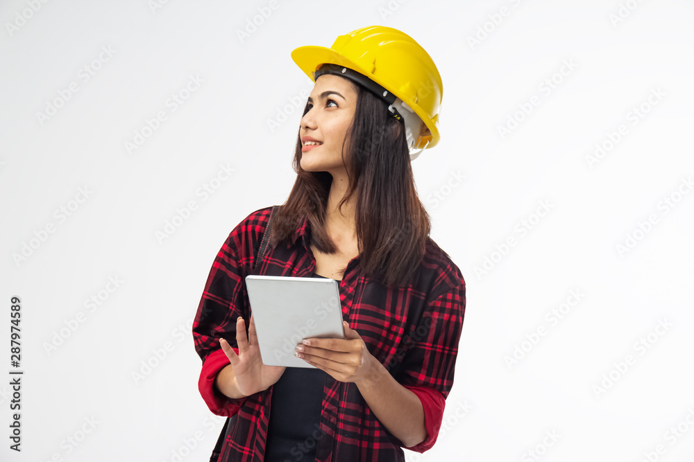 The young woman engineer put yellow safety helmet on her head,using tablet for checking data,with smile and happy feeling,good work,good job The young woman engineer put yellow safety helmet on her head,using tablet for checking data,with smile and happy feeling,good work,good job