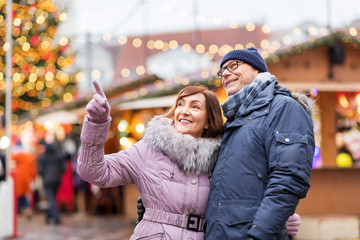 travel, tourism, holidays and people concept - happy senior couple hugging at christmas market on town hall square in tallinn, estonia
