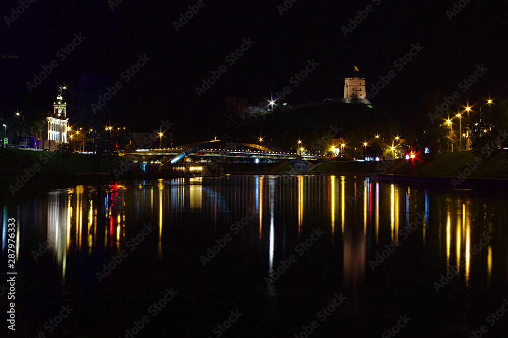 Night time cityscape of Vilnius with the street lights reflecting in water.