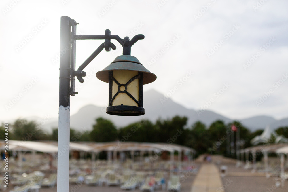 Street lamp on the beach. In the background is a beautiful view of the mountains.