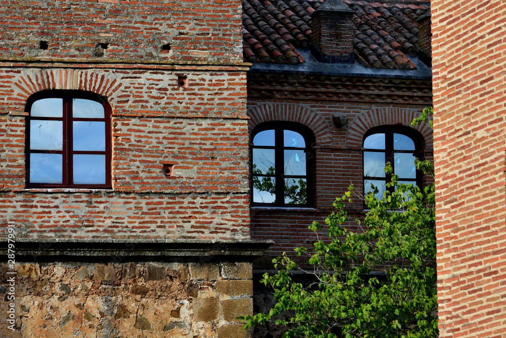 Blue sky reflection in the windows of an old brick building between lights and shadows