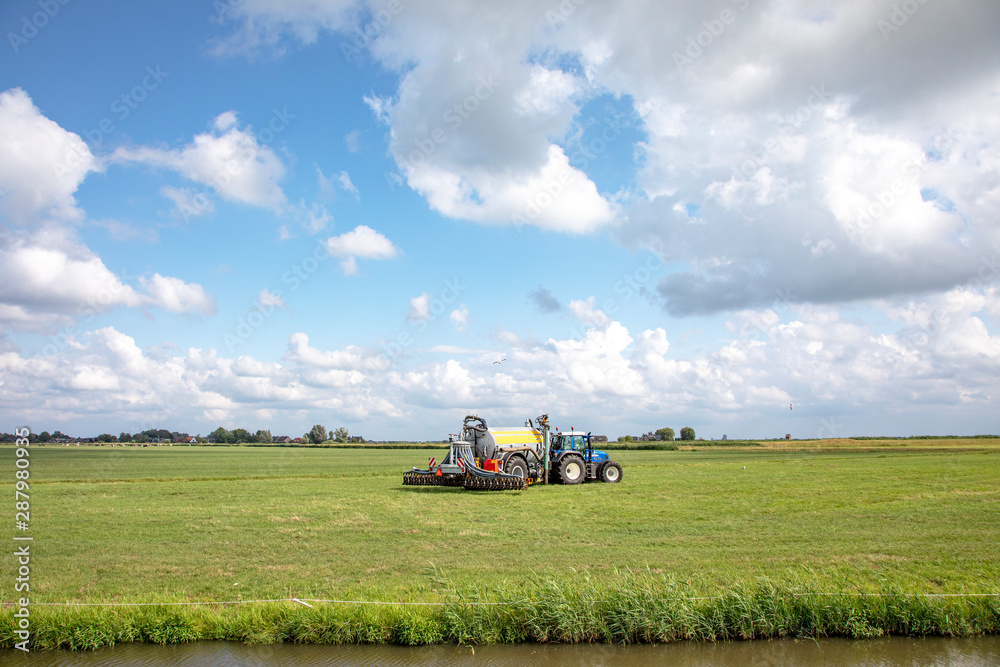 Agricultural tractor drives through field under a blue cloudy sky. Agricultural tractor drives through field under a blue cloudy sky.