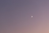 Evening gradient purple pink peach sky with crescent moon. Copy space