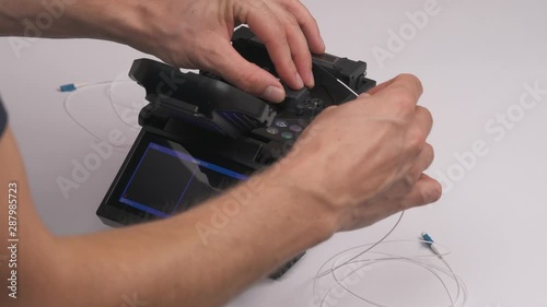 Close-up of male technician splicing two fiber optic internet cable together using a machine which melts the glass together.