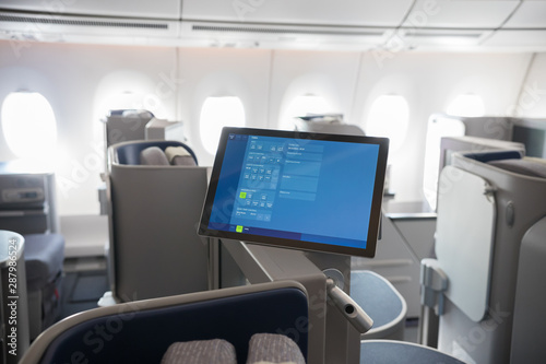A business class clean cabin of the airplane - monitors hanging in front of the chairs
