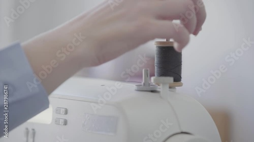 Wallpaper Mural Close-up hand of seamstress inserts a spool of thread into a sewing machine before starting work. Concept of job, profession, hobby Torontodigital.ca