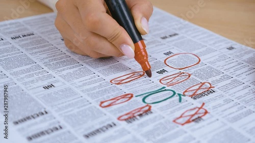 woman Looking for Job in a Newspaper and Marking Advertisement Using Red Pencil. 4K